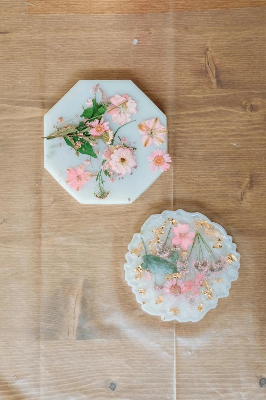 a couple of plates sitting on top of a wooden table, pressed flowers, silicone cover, soap carving, all marble