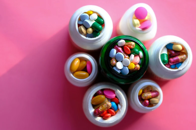 a group of pill bottles sitting on top of a pink surface, intricate colorful, jar on a shelf, thumbnail, formulas