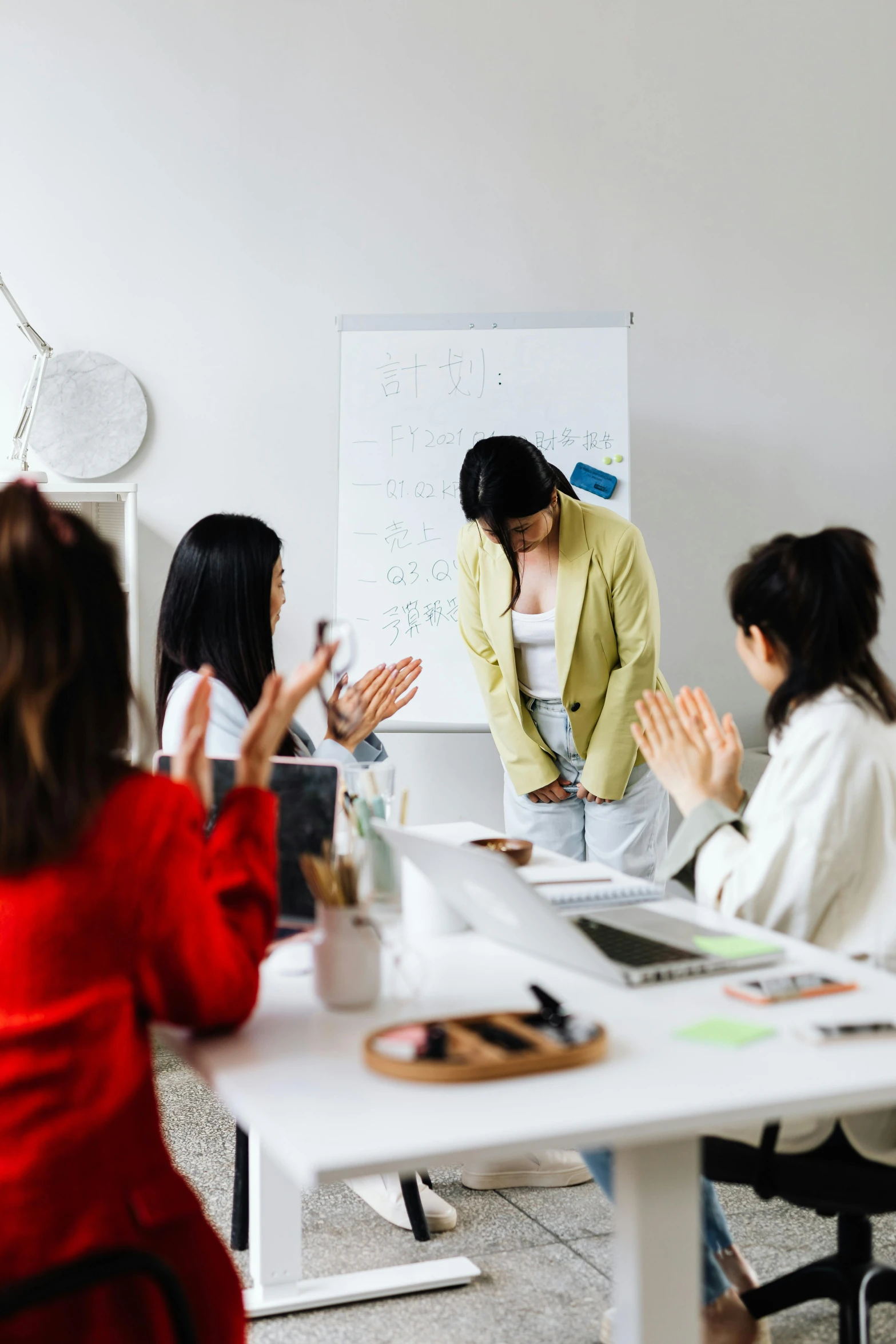 a group of people sitting around a table clapping, pexels contest winner, arbeitsrat für kunst, standing on a desk, asian female, ui and ux, white wall coloured workshop