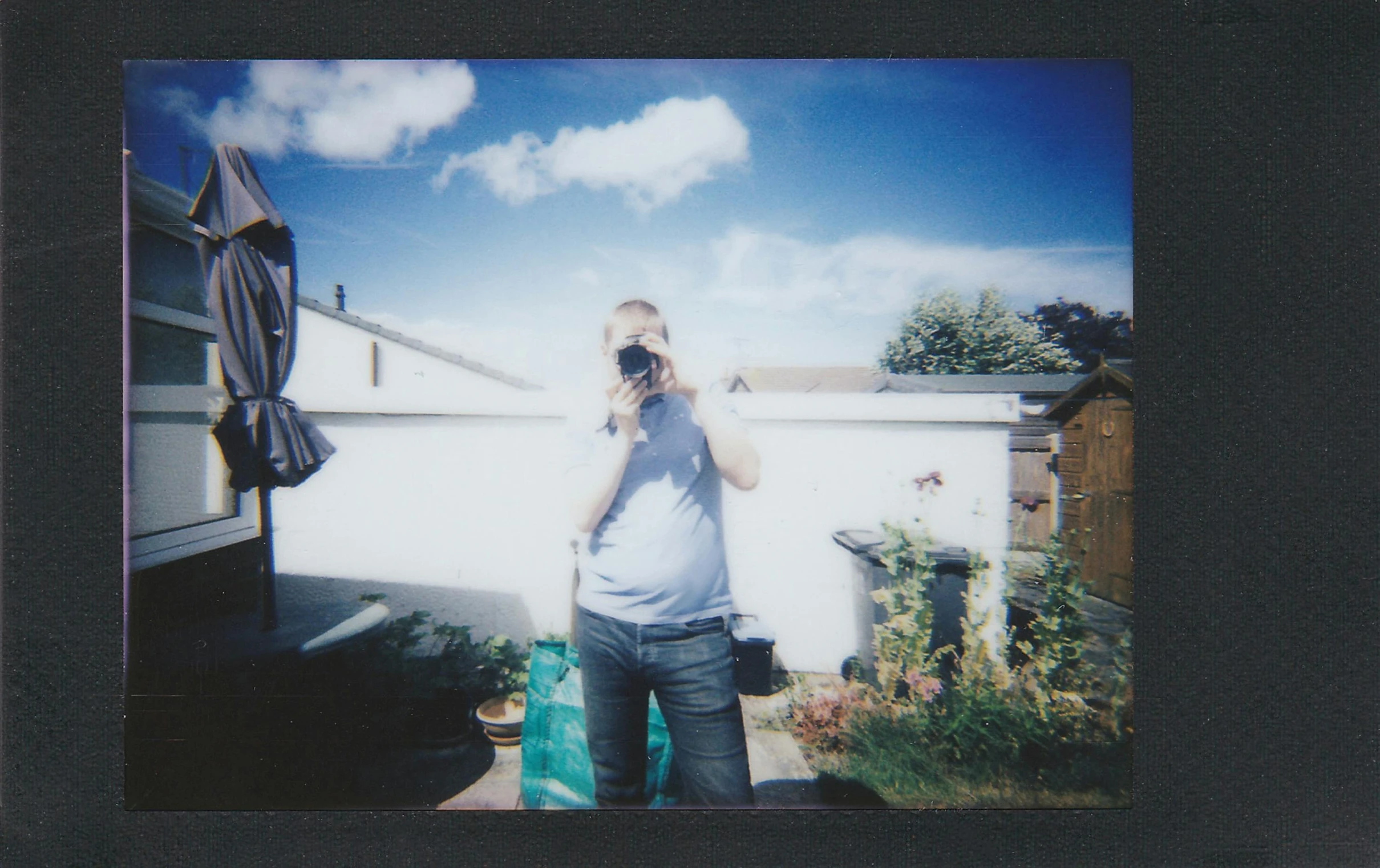 a man taking a picture of himself with a camera, a polaroid photo, by David Begbie, solarised, standing outside a house, 35mm —w 1920 —h 1080, medium format