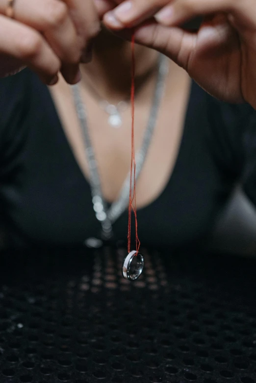 a close up of a person holding a string, onyx, sitting down, on display, raindrop