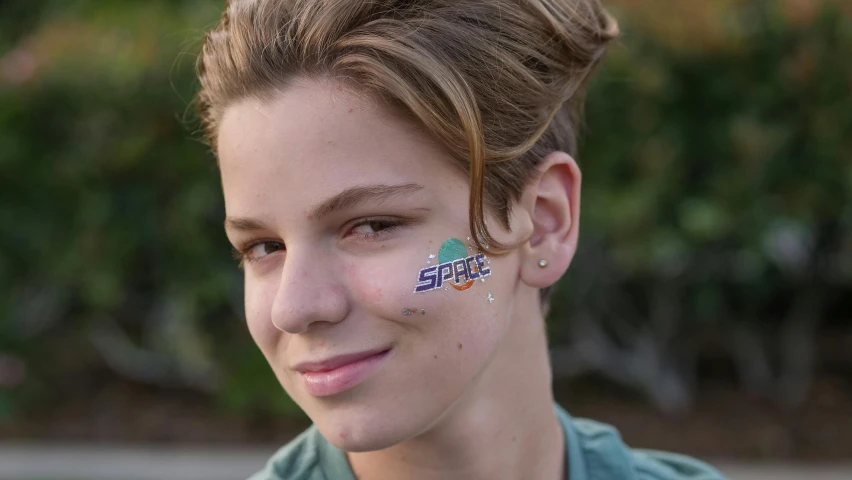a close up of a person with a face paint, spacehip lands, young teen, stickers, sploch