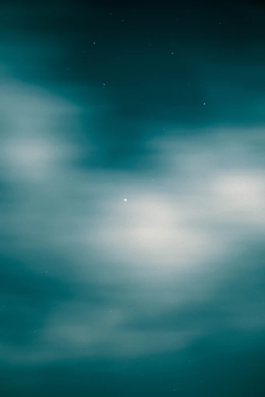 a large body of water under a cloudy sky, a minimalist painting, by Adam Pijnacker, unsplash, light and space, sirius star system, teal aesthetic, blurry photography, white cyclops portrait in sky