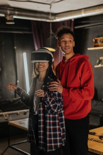 a couple of people standing next to each other, a hologram, trending on pexels, vr helmet, teenager hangout spot, shot with sony alpha, production photo