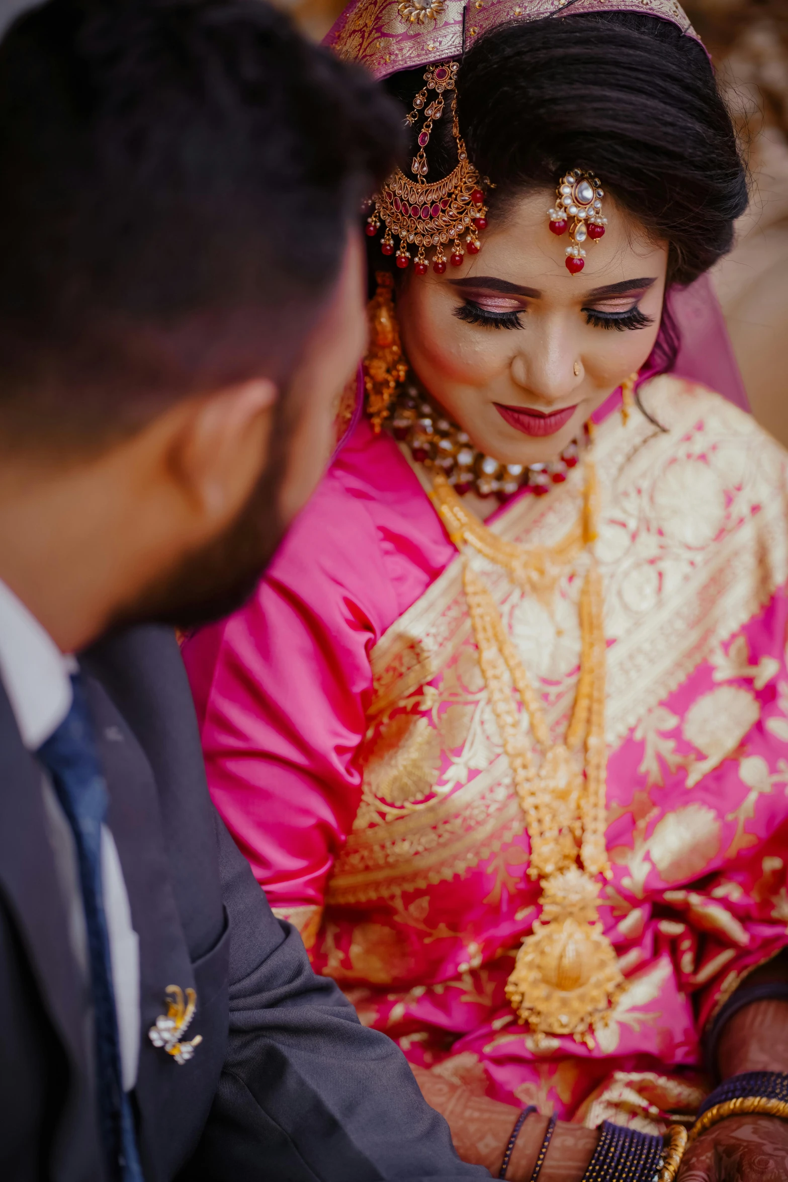 a man and woman sitting next to each other, pexels contest winner, hurufiyya, hot pink and gold color scheme, bangladesh, bride, woman's face looking off camera