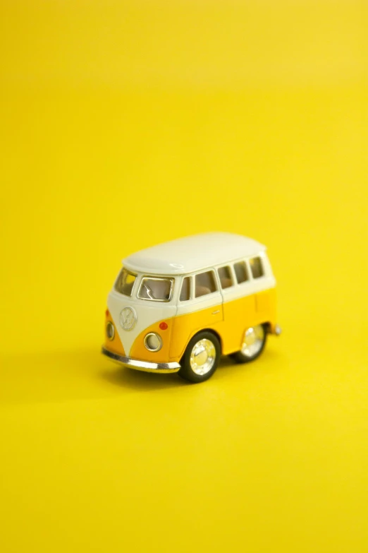 a toy van sitting on top of a yellow surface, a picture, unsplash, microbus, cream, bright white light, enamel