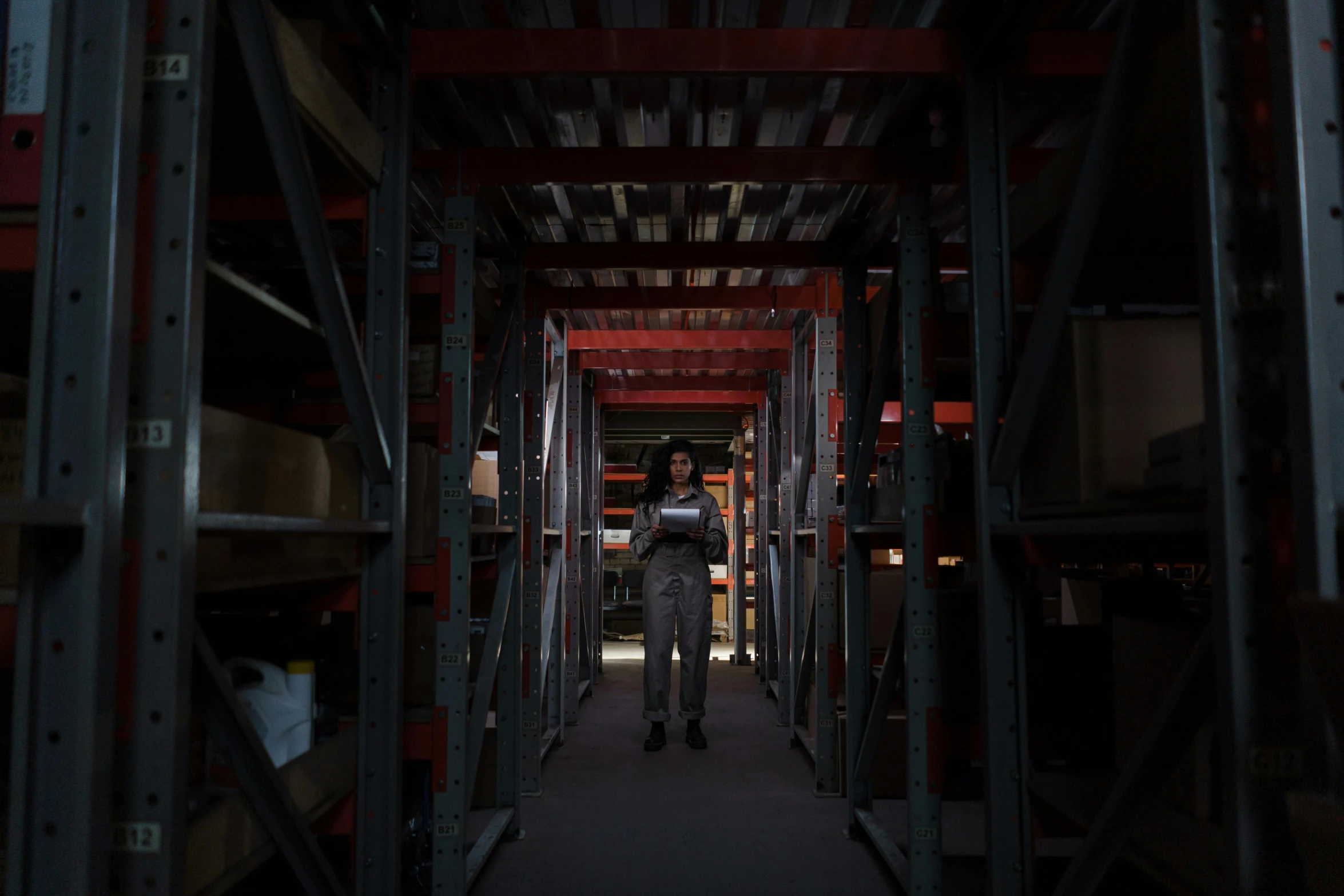 a man standing in a warehouse holding a tablet, inspired by Elsa Bleda, serial art, 8k 28mm cinematic photo, weta studios, the librarian, cinematic outfit photo