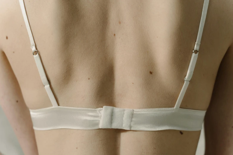 the back of a woman wearing a white bralet, inspired by Man Ray, up close image, soft white rubber, alessio albi, detailed product image