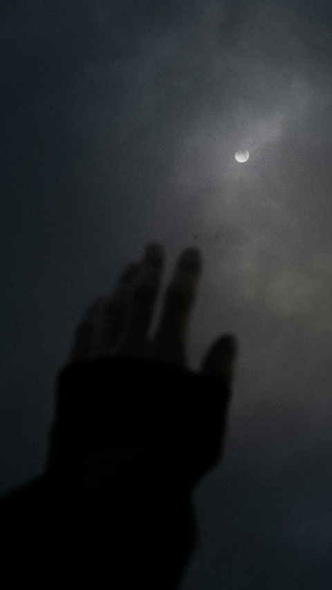 a person's hand reaching up to the moon, inspired by Jan Rustem, dark solar eclipse, overcast!!!, low quality photo, image