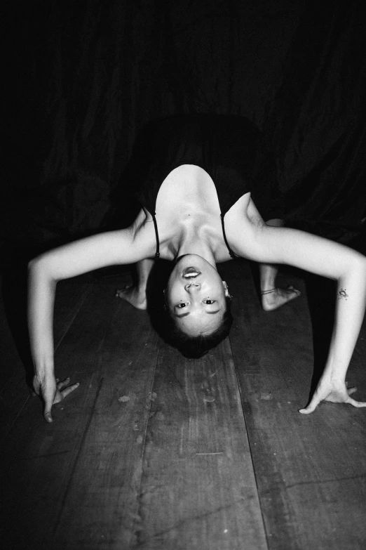 a black and white photo of a woman doing a handstand, inspired by Marina Abramović, ✨🕌🌙, done in the style of caravaggio, björk, looking down at you