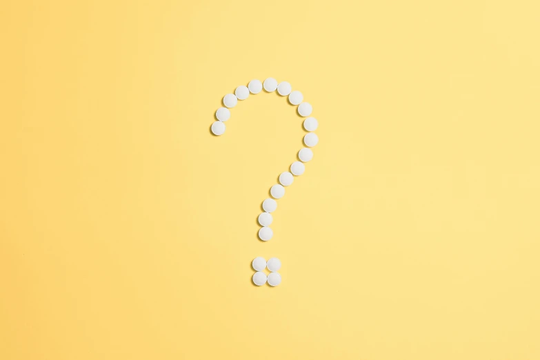 a question mark made out of pills on a yellow background, a stock photo, by Adam Marczyński, trending on pexels, pearl necklace, on a pale background, 8 k what, a round minimalist behind