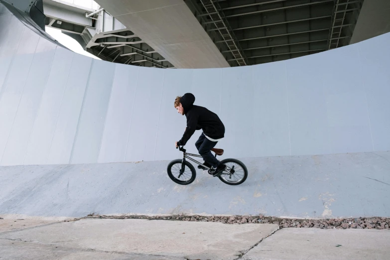 a man riding a bike up the side of a ramp, inspired by Seb McKinnon, urban playground, stealthy, riding a bike, on the streets