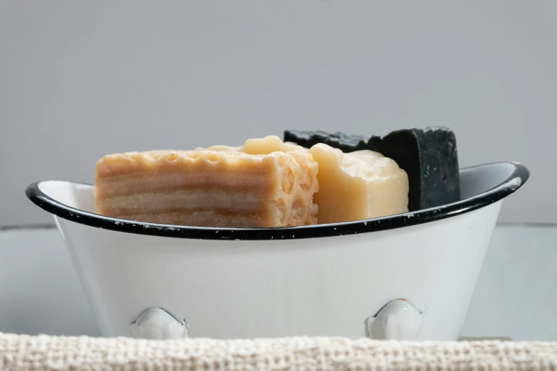 a bowl of soap sitting on top of a table, inspired by Einar Hakonarson, bauhaus, ( ivory black ), closeup at the food, threes, various posed