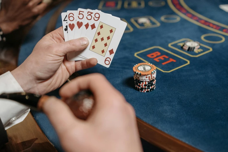 a close up of a person holding playing cards, a screenshot, by Kristian Zahrtmann, pexels contest winner, gaming table, épaule devant pose, pair of keycards on table, thumbnail