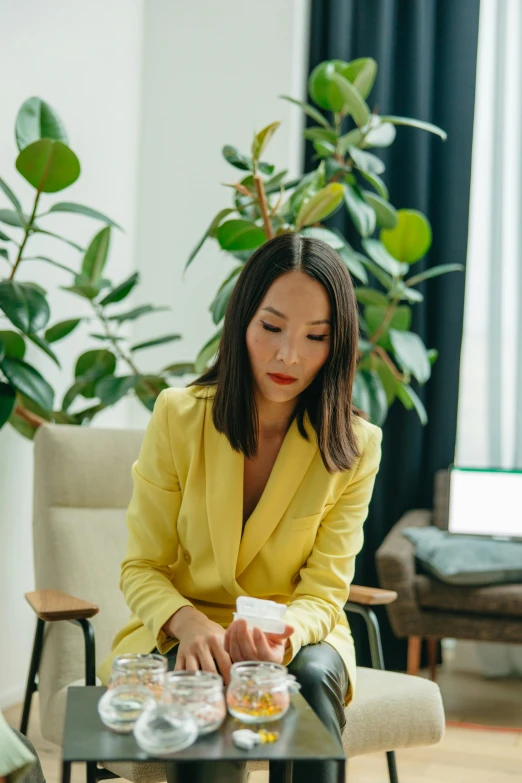 a woman sitting on a chair in a living room, by Julia Pishtar, pexels contest winner, yellow clothes, in a business suit, asian descent, loputyn and matcha