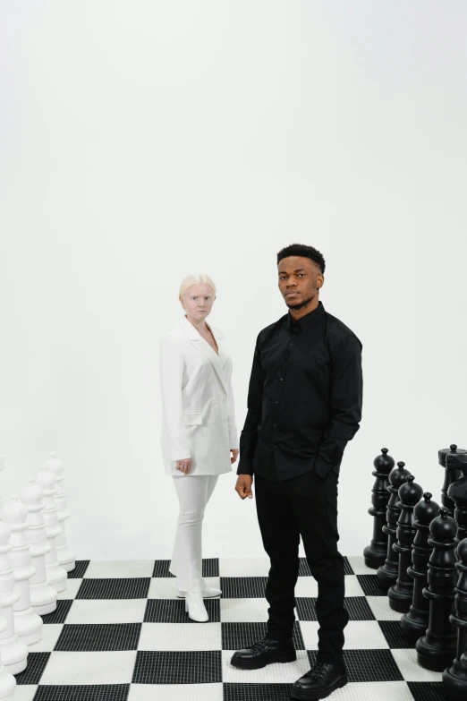 a man and a woman standing in front of a chess board, an album cover, pexels contest winner, an all white human, mkbhd, albino white pale skin, wearing causal black suits