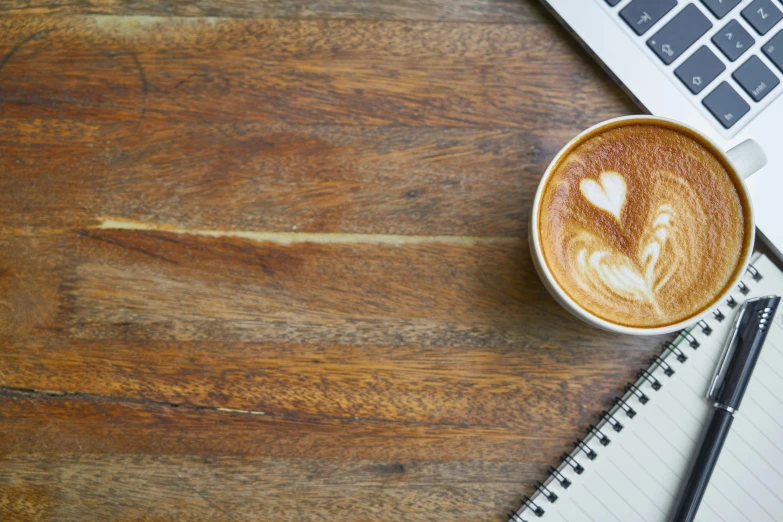 a cup of coffee sitting on top of a wooden table, by Carey Morris, trending on unsplash, computer art, 9 9 designs, notebook, background image