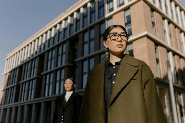 a couple of people standing in front of a building, inspired by Fei Danxu, pexels contest winner, academic clothing, wearing a long coat, girl wearing uniform, serious business