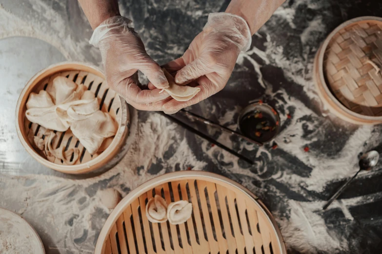 a person holding a dumpling in one hand and chopsticks in the other, trending on pexels, process art, white bandages on fists, ingredients on the table, steamed buns, marbling