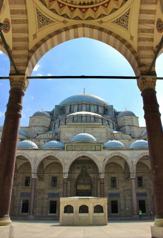 a large building with a dome on top of it, inspired by Osman Hamdi Bey, hurufiyya, white stone arches, blue, center of image, -