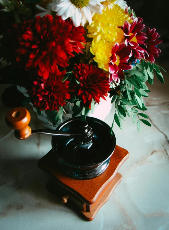 a vase of flowers sitting on top of a table, a still life, by Julia Pishtar, unsplash, celebration of coffee products, pestle, black steel with red trim, dahlias