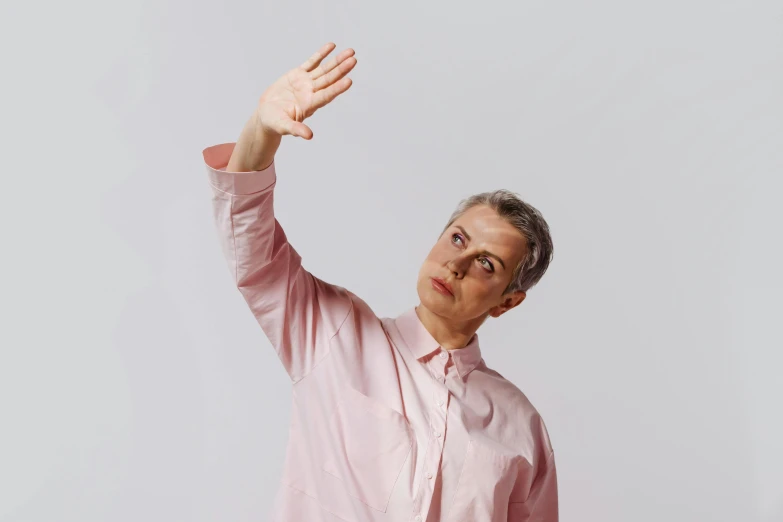 a woman in a pink shirt throwing a frisbee, by Marina Abramović, unsplash, neo-dada, holding his hands up to his face, pale grey skin, peter capaldi, non binary model