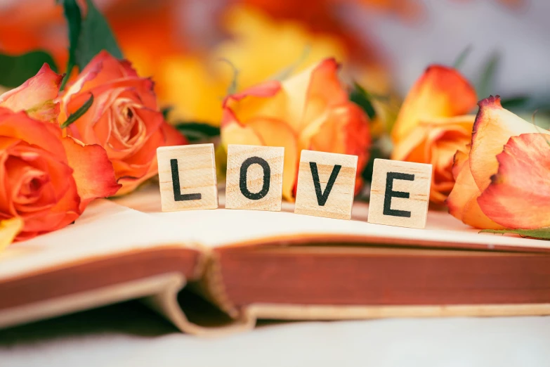 a book sitting on top of a table next to a bunch of flowers, love theme, finding words, thumbnail, letters