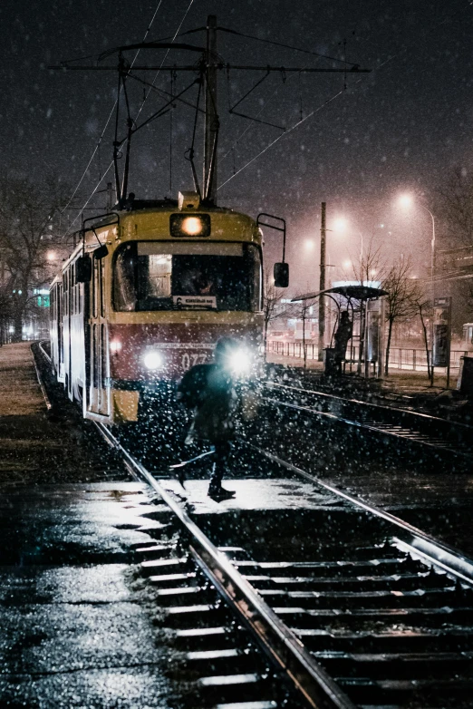 a train traveling down train tracks at night, by Adam Szentpétery, pexels contest winner, dusting of snow, street tram, soviet, 🚿🗝📝