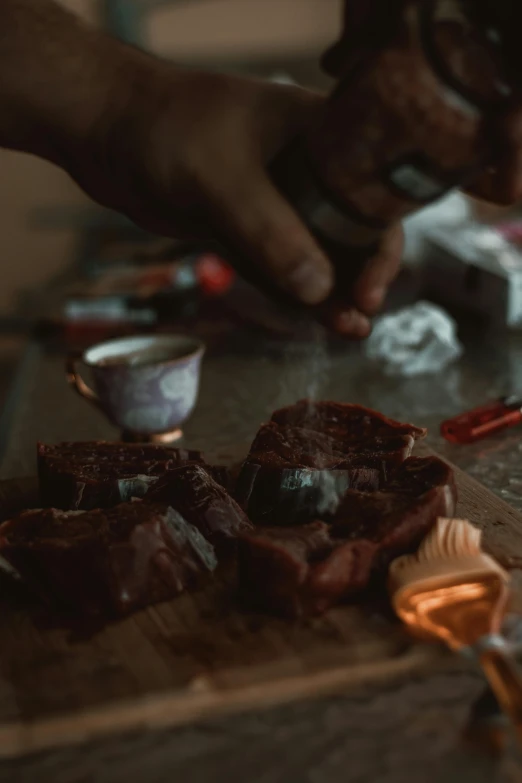 a close up of a person cutting food on a cutting board, a still life, by Jacob Toorenvliet, pexels contest winner, process art, taking tobacco snuff, smothered in melted chocolate, with red haze, clay amulets