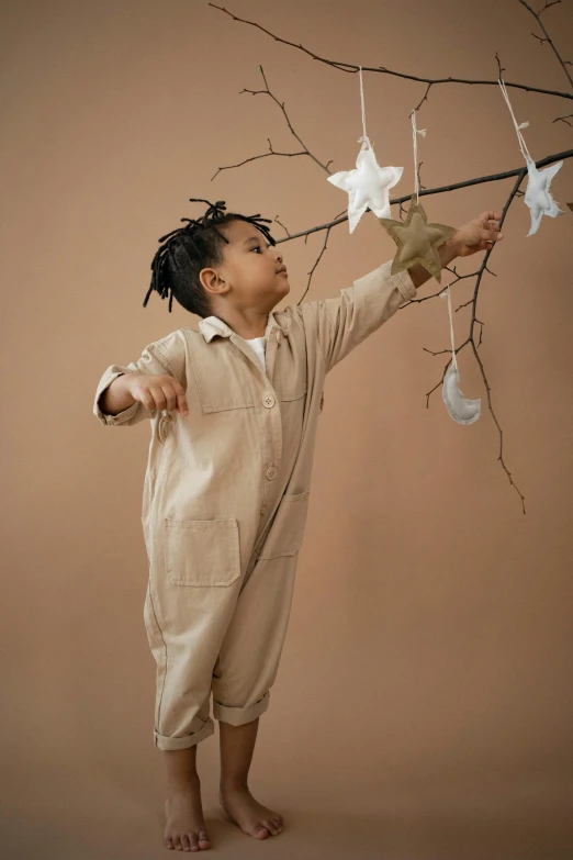 a little girl holding onto a branch of a tree, an album cover, inspired by Louis Le Nain, pexels contest winner, jumpsuits, beige color scheme, star child, clay