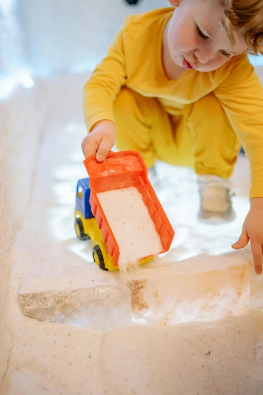 a little boy that is playing in some sand, by Julia Pishtar, pexels contest winner, process art, made of ice, vehicle, building blocks, snow cave