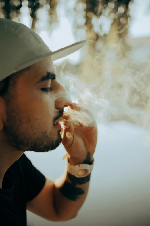 a man in a hat smokes a cigarette, inspired by Elsa Bleda, pexels contest winner, lean man with light tan skin, profile pic, nug pic, concentrated