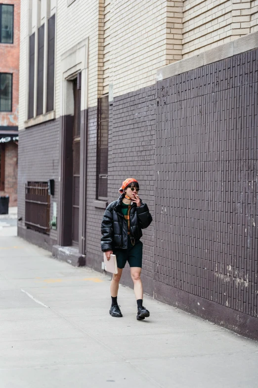 a woman walking down a sidewalk talking on a cell phone, trending on unsplash, visual art, bra and shorts streetwear, a man wearing a black jacket, non binary model, new york alleyway