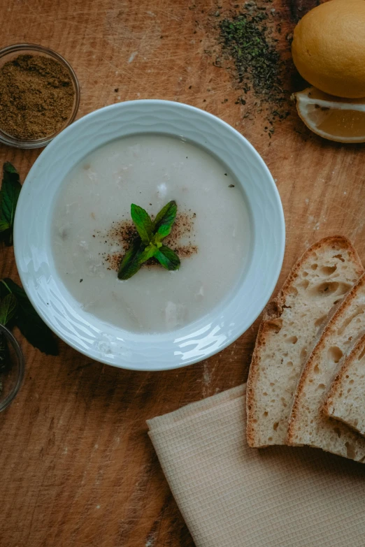 a wooden table topped with bread and a bowl of soup, inspired by Géza Dósa, unsplash, mint, vanilla, square, thumbnail