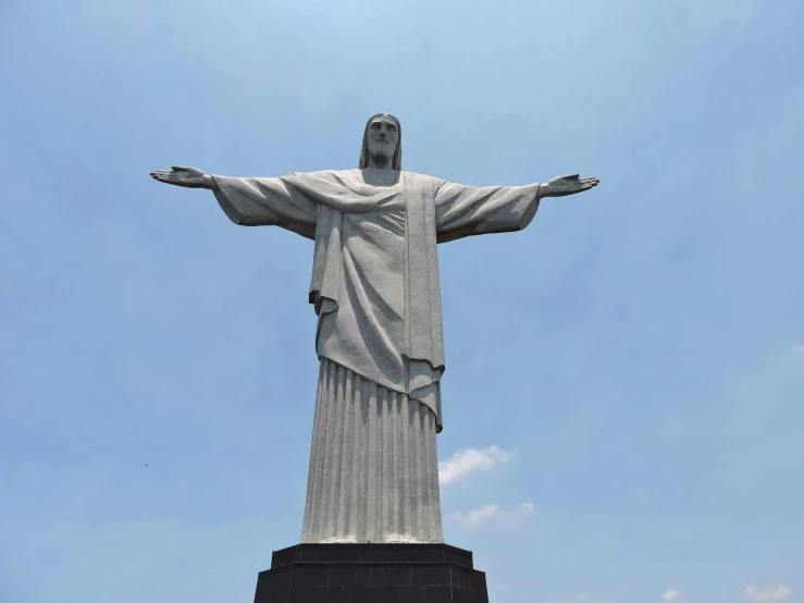 a statue of jesus stands in front of a blue sky, by Matteo Pérez, pexels contest winner, hyperrealism, cristo redentor, grey, front side, helio oiticica