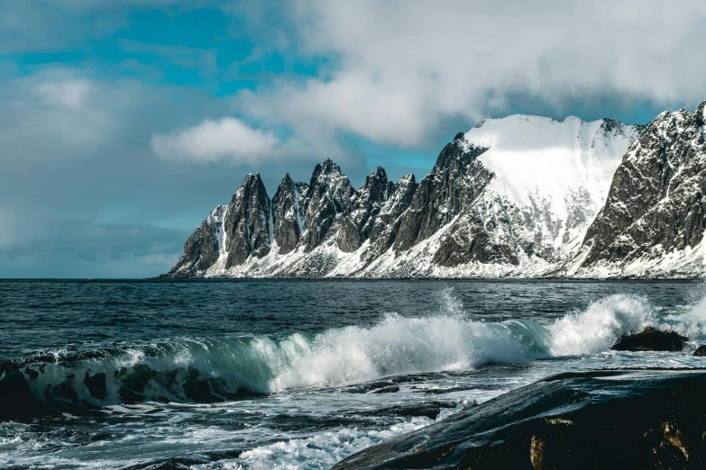 a body of water with a mountain in the background, by Tom Wänerstrand, pexels contest winner, waves crashing in the sea, snowy arctic environment, thumbnail, devils horns