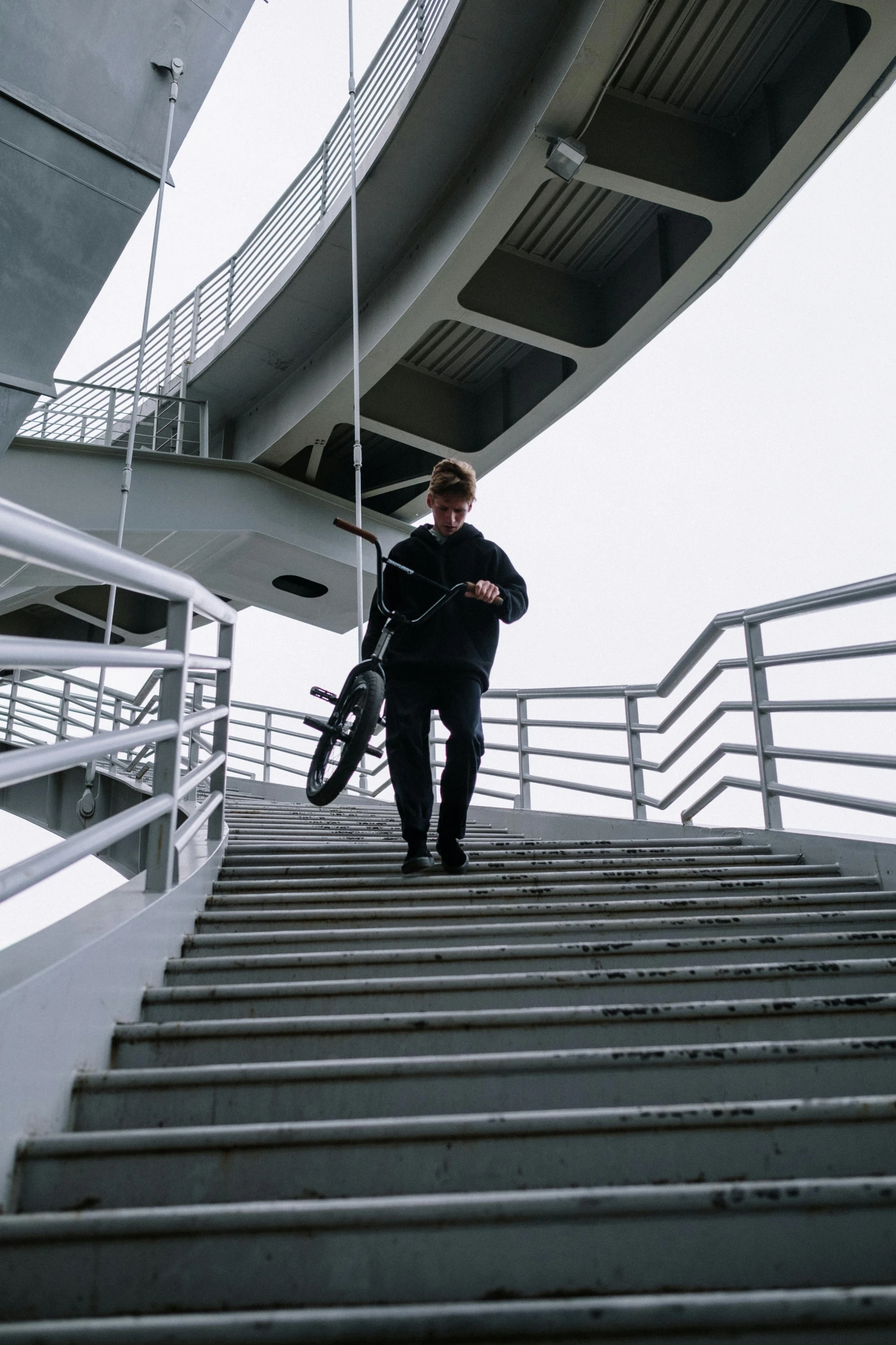 a man walking up a flight of stairs, unsplash, picture of a male biker, techwear clothes, tall thin build, bridge