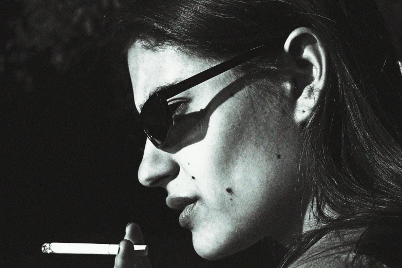 a black and white photo of a woman smoking a cigarette, inspired by Elsa Bleda, flickr, wearing shades, gendo ikari smoking a joint, close - up profile, taken in the late 2000s