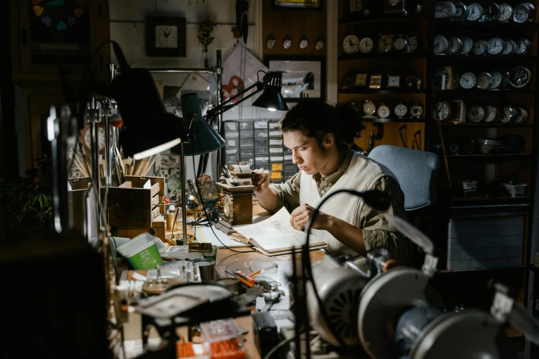 a woman sitting at a desk working on a piece of paper, by Meredith Dillman, pexels contest winner, arts and crafts movement, exposed wires and gears, in his basement studio, a handsome, weta disney