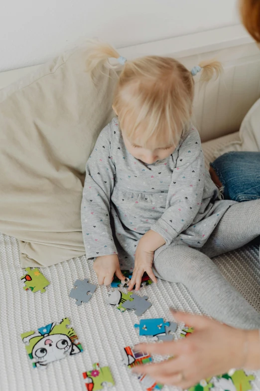 a woman playing with a child on a couch, a jigsaw puzzle, by Nicolette Macnamara, grey clothes, toddler, zoomed in, bedhead