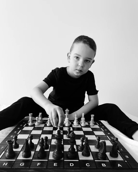 a black and white photo of a boy playing chess, by Silvia Pelissero, happening, confident pose, posed, ilustration, instagram picture