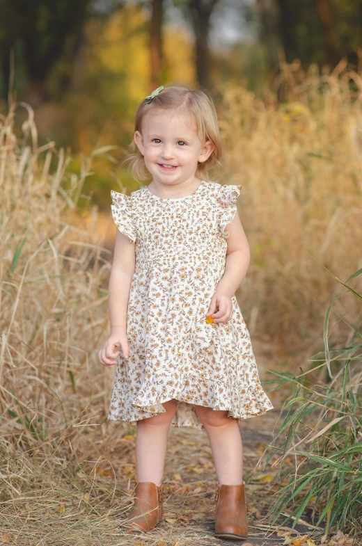 a little girl standing in a field of tall grass, swirly flower dress, vanilla, amber, zoomed in