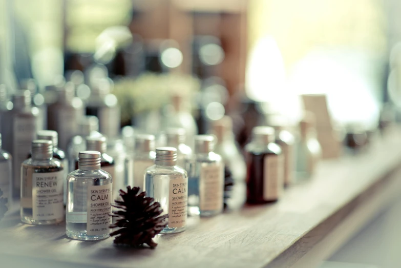 a row of bottles sitting on top of a wooden shelf, a tilt shift photo, by Sylvia Wishart, unsplash, silver，ivory, spa, pine, clear makeup