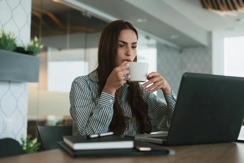 a woman sitting at a table with a laptop and a cup of coffee, trending on pexels, avatar image