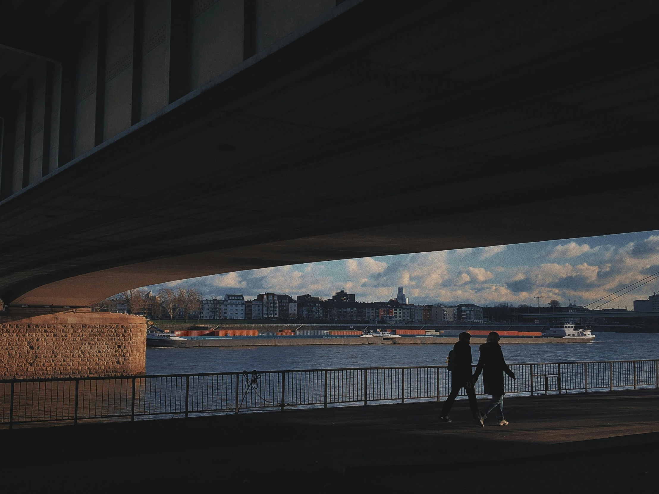 two people walking under a bridge next to a body of water, by Tobias Stimmer, unsplash contest winner, visual art, graded with davinci resolve, budapest street background, medium format. soft light, helsinki