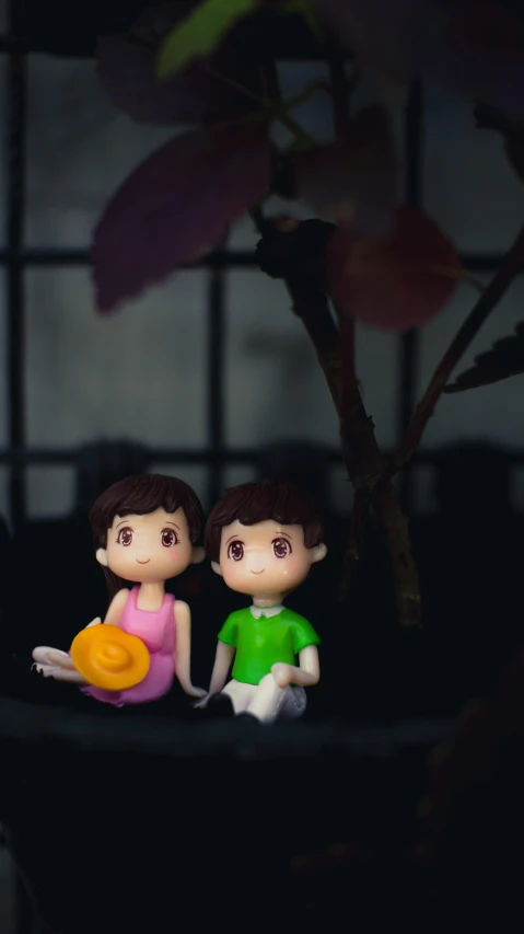 a couple of figurines sitting on top of a table, a cartoon, inspired by Nara Yoshitomo, pexels contest winner, sitting under a tree, lofi girl, plasticine, evening time