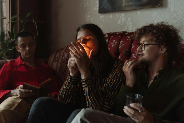 a group of people sitting on top of a couch, inspired by Nan Goldin, pexels, hyperrealism, praying with tobacco, still from a wes anderson movie, three women, bathed in the the glow of a fire