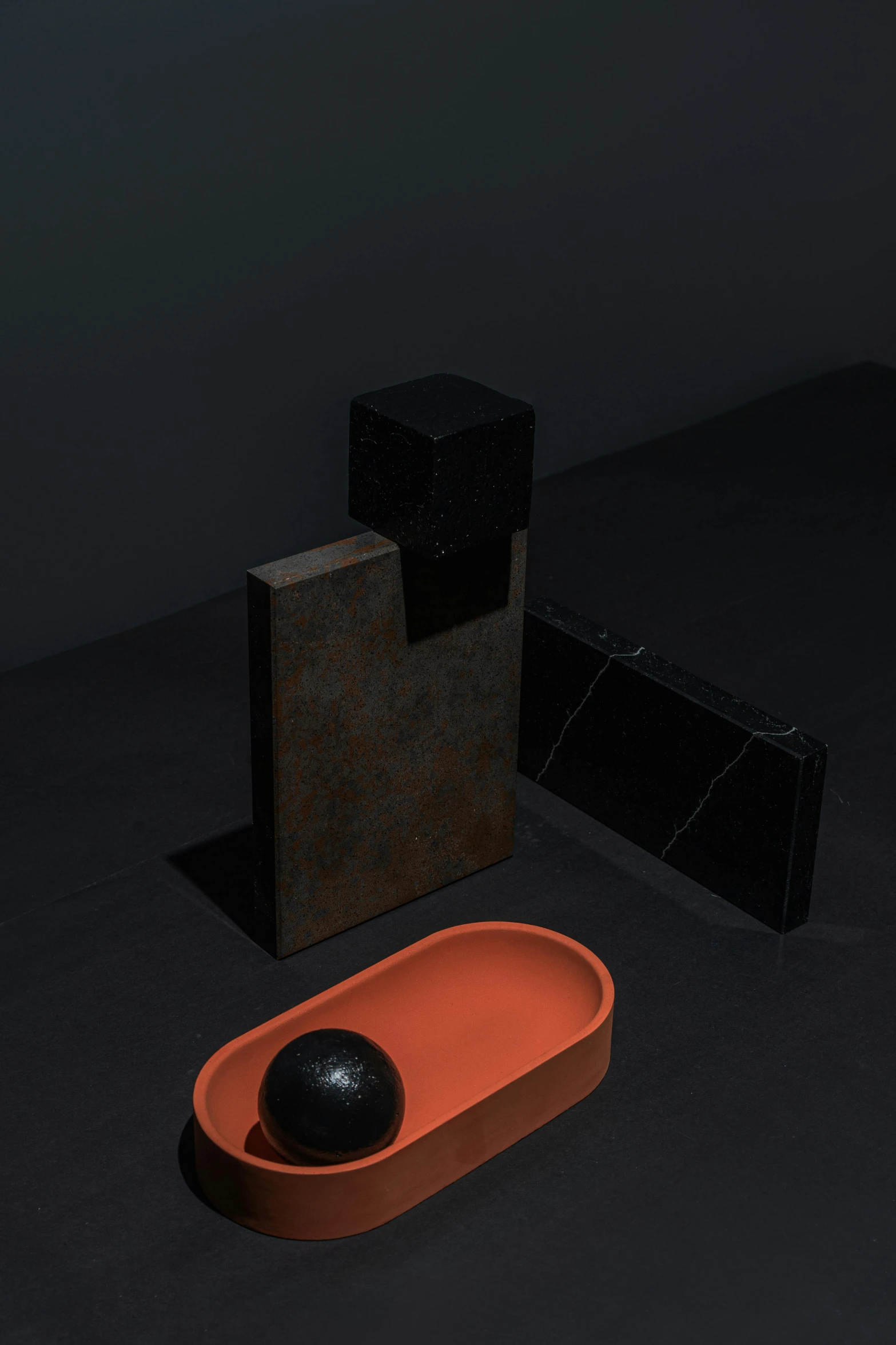 a black and orange object sitting on top of a table, an abstract sculpture, conceptual art, ((monolith)), ignant, vignette, minimal artifacts