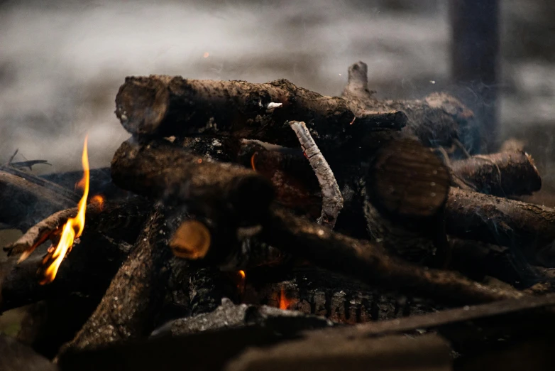 a pile of wood sitting on top of a fire, by Daniel Lieske, pexels contest winner, rain and smoke, brown, floating embers, background image