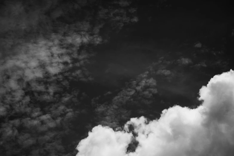 a black and white photo of a plane in the sky, a black and white photo, unsplash, minimalism, cloud nebula, high contrast 8k, low angle photo, dark cloudy sky